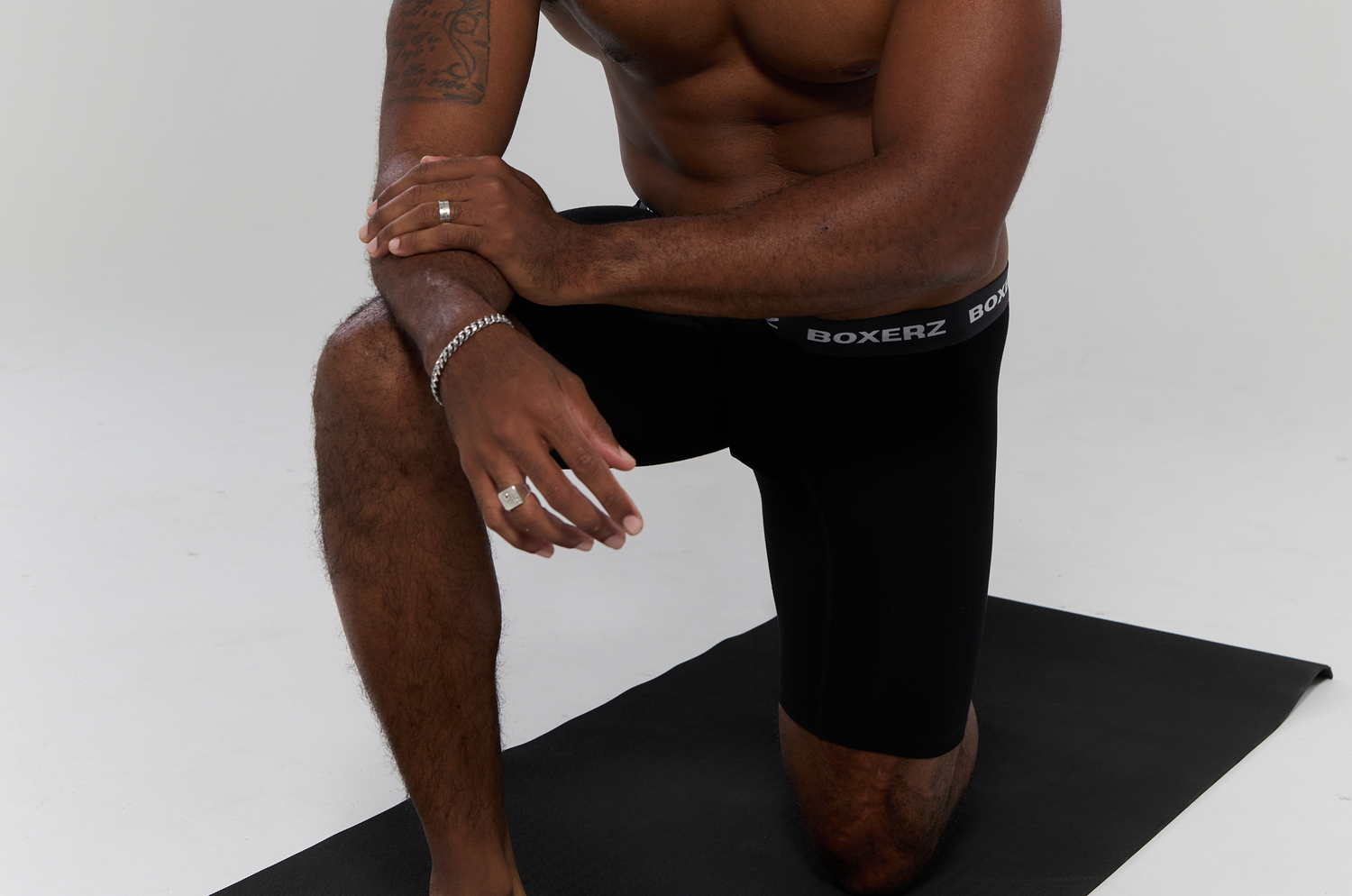Athletic man in black BOXERZ boxer briefs kneeling on yoga mat, highlighting breathable and stretchable men's active underwear.
