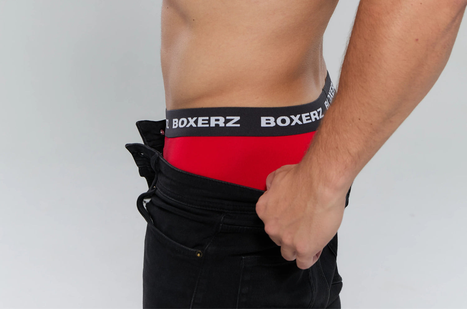 Man pulling down pants to reveal red Boxer Briefs with black BOXERZ waistband