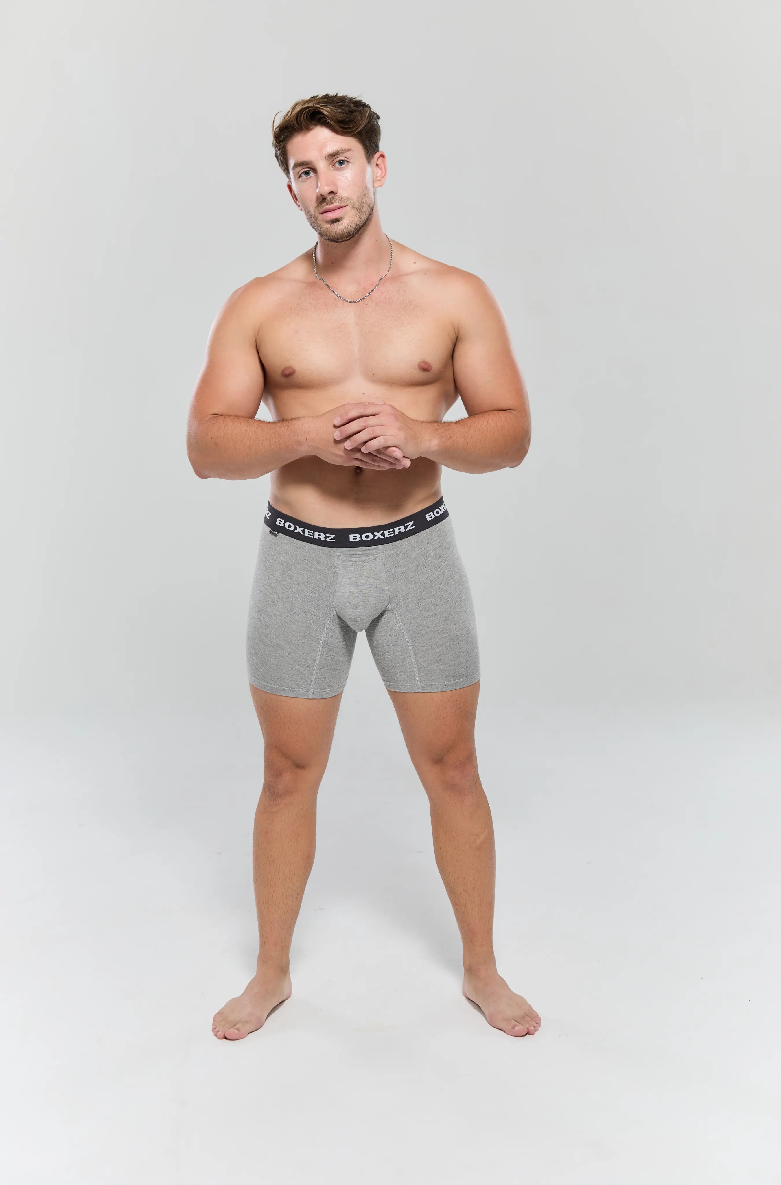 Full body front view of male model wearing grey boxer briefs from Boxerz, showing tailored fit and logo waistband