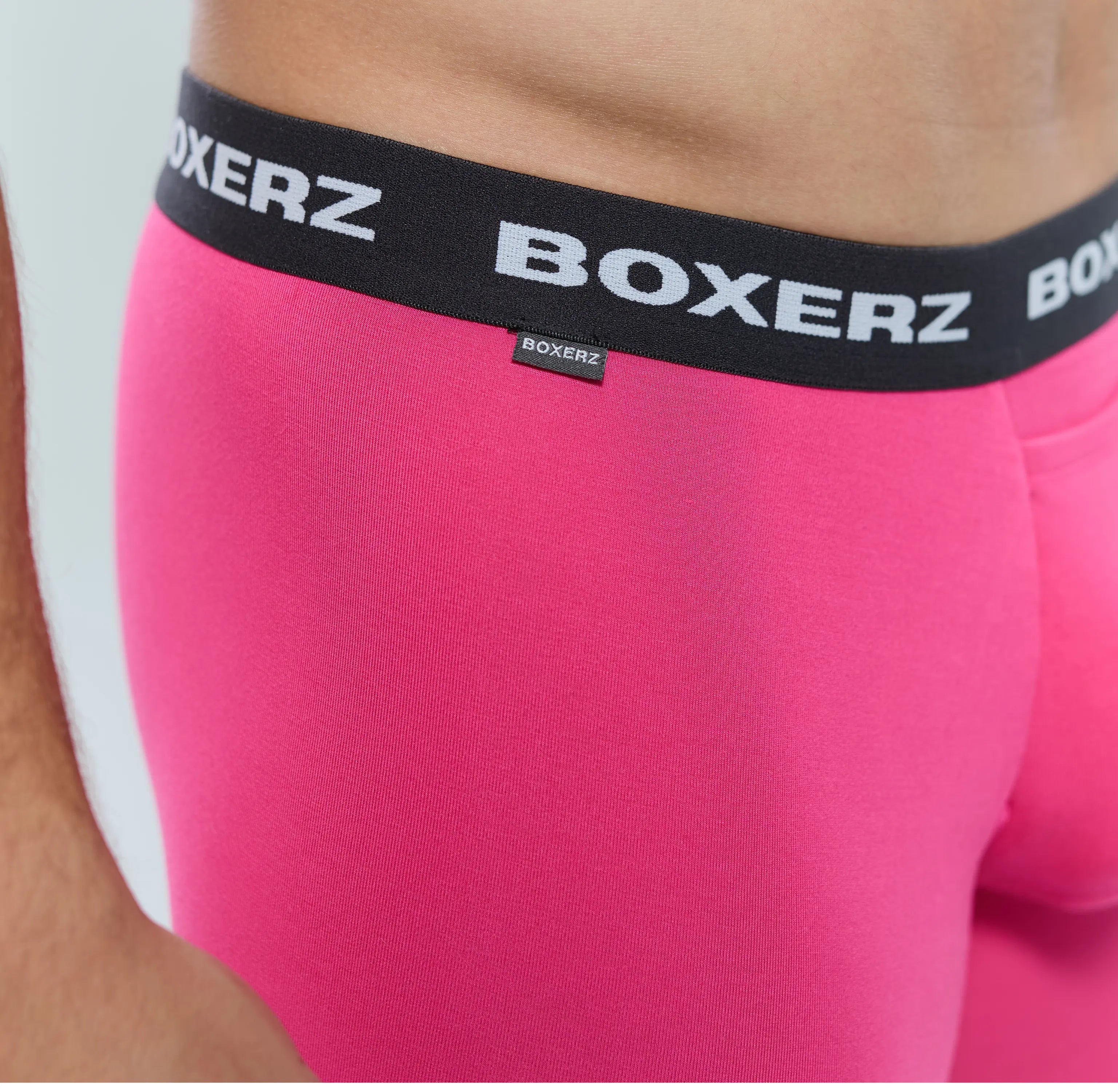 Close-up of Boxerz waistband on pink boxer briefs, showing logo and stitching details