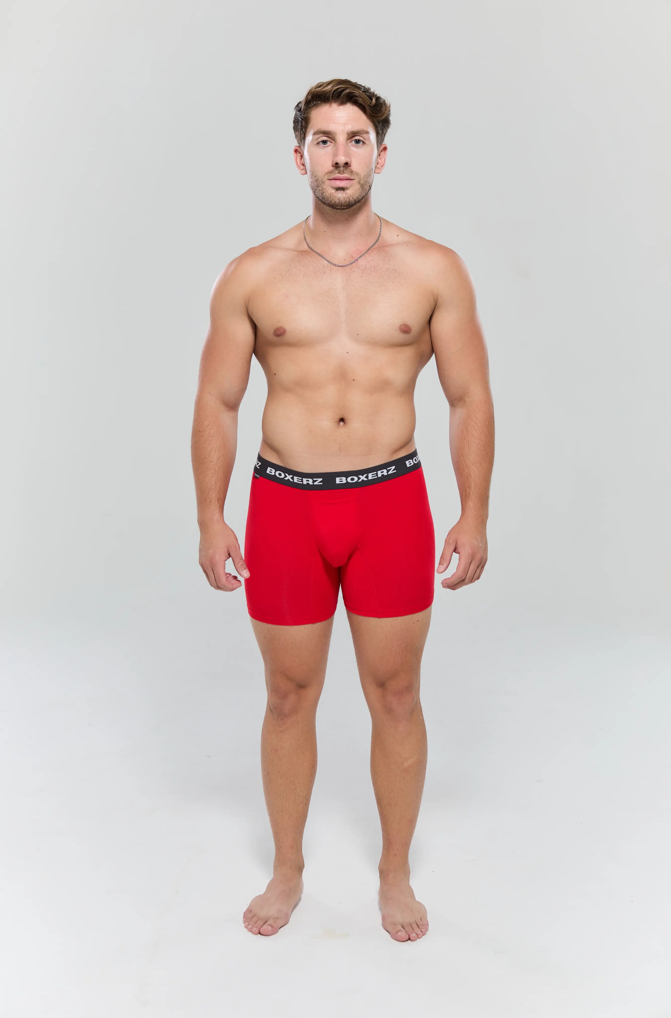 Full body front view of male model wearing red boxer briefs from Boxerz, showing tailored fit and logo waistband